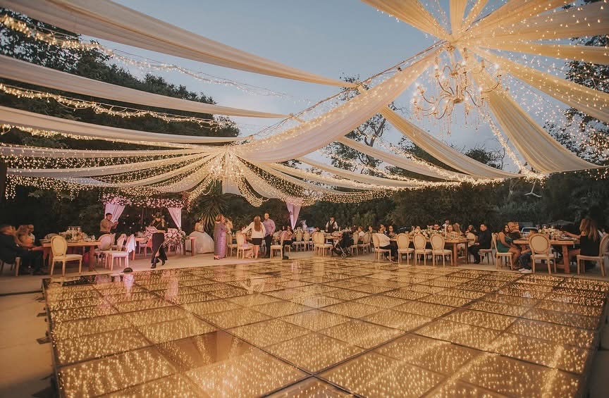 Carpa con luces y candelabro sobre la pista de baile en el jardín Kantiek de Rancho El Beg